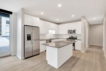 A kitchen with white cabinets and a stainless steel refrigerator